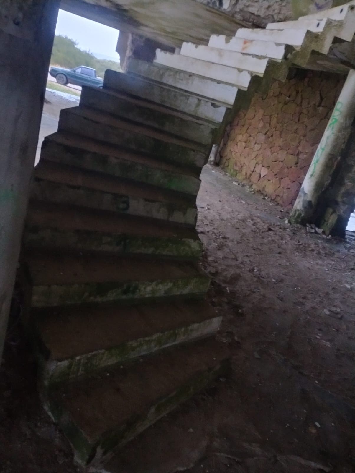 Escalera de hormigón deteriorada dentro del edificio.