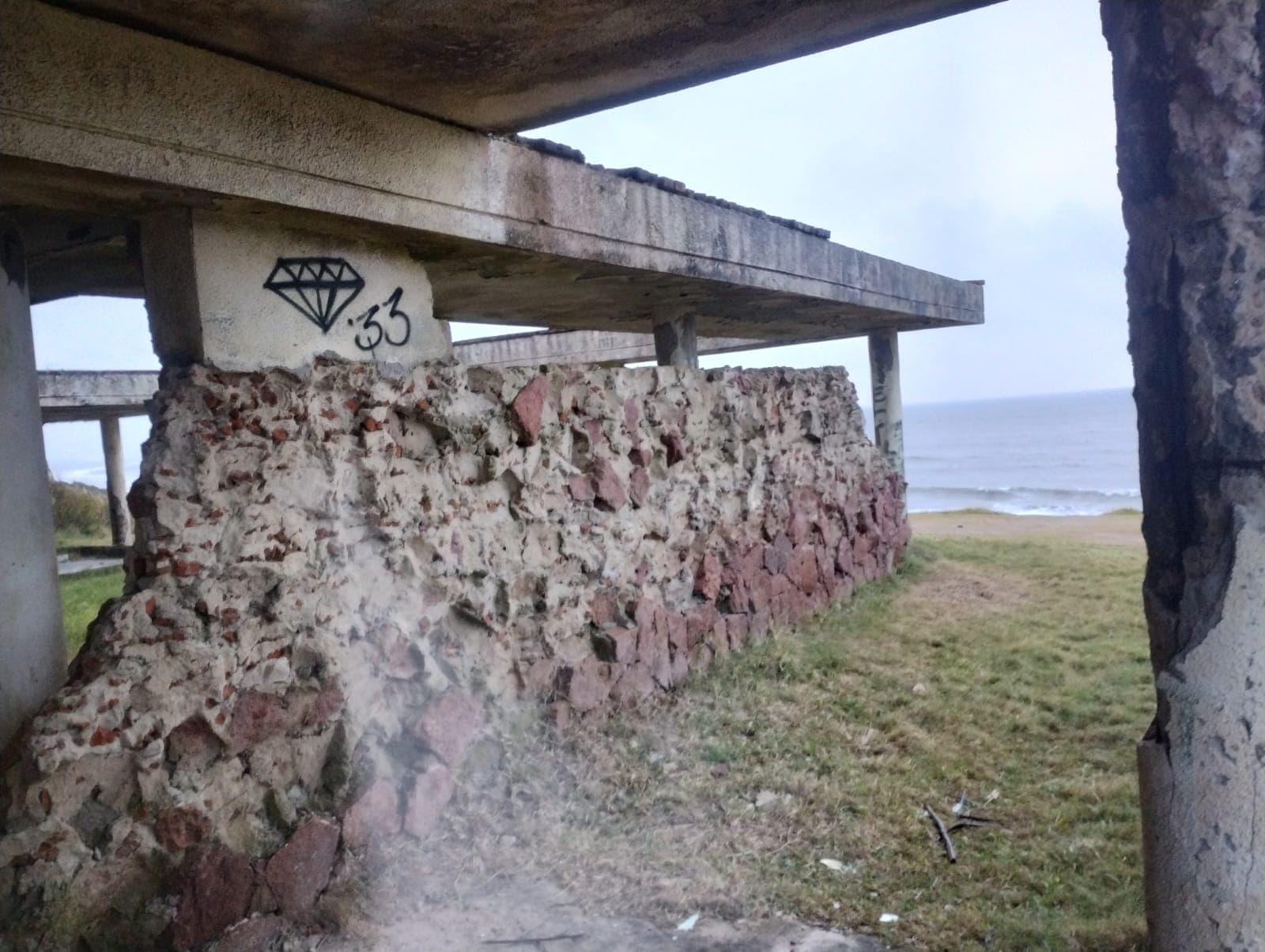 Muro de piedra original con apertura hacia el mar dentro del antiguo hotel.