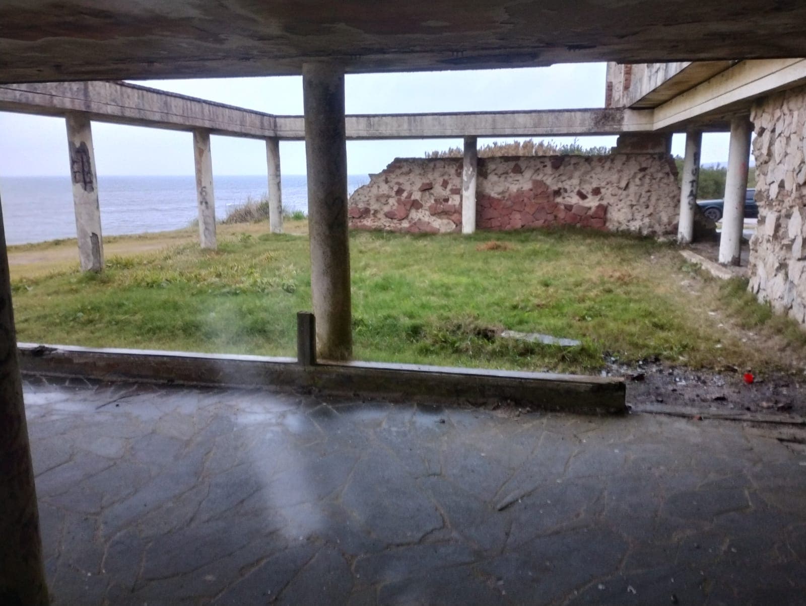 Patio cubierto con muro de piedra y apertura hacia el océano.