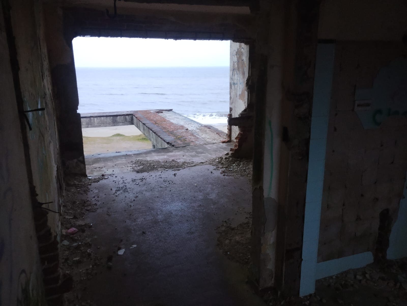 Salón interior abierto con vista al mar a través de una gran abertura.